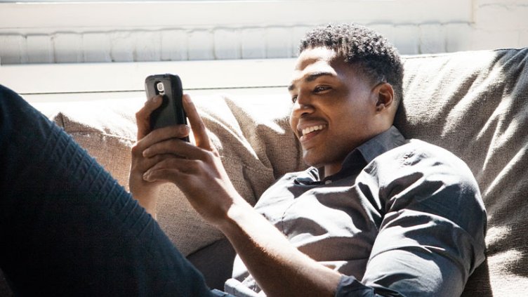 Happy Man sitting on sofa and looking at messages on phone